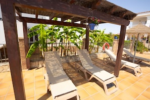 Ein überdachter Außenbereich mit Liegestühlen und einer Pergola.