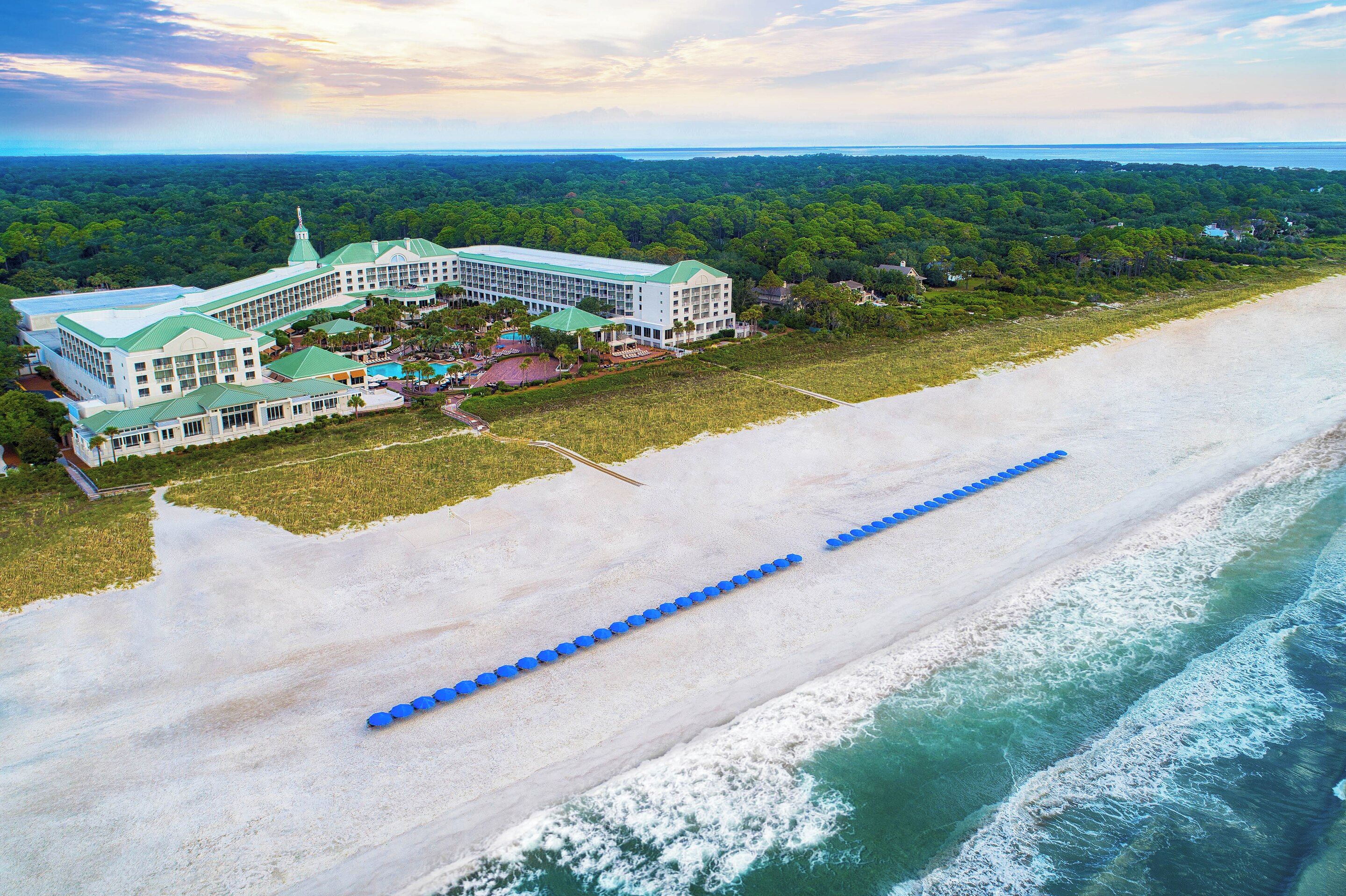 Un gran resort con varias edificaciones, acceso directo a la playa y una larga barrera azul a lo largo de la costa.
