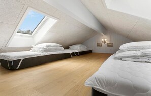 Ein Zimmer mit schrägen Wänden, einem Oberlicht und zwei Betten inklusive Matratzen.