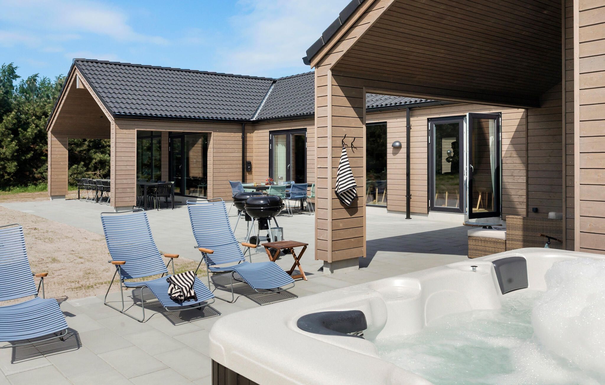 Un espace extérieur abrité comprenant des chaises longues, un barbecue et un jacuzzi.