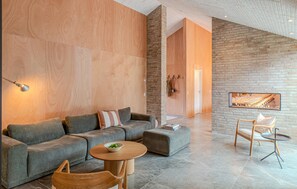 Una sala moderna con un sofá modular, una mesa de centro redonda y una silla minimalista.