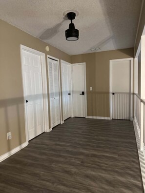 A hallway with a ceiling fan, white doors, and a wooden floor. - Waterfront Retreat in Jacksonville (Jacksonville)