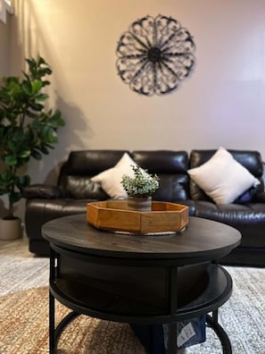 A round coffee table with a wooden tray and a small plant in the center, placed on a carpeted floor. - Waterfront Retreat in Jacksonville (Jacksonville)
