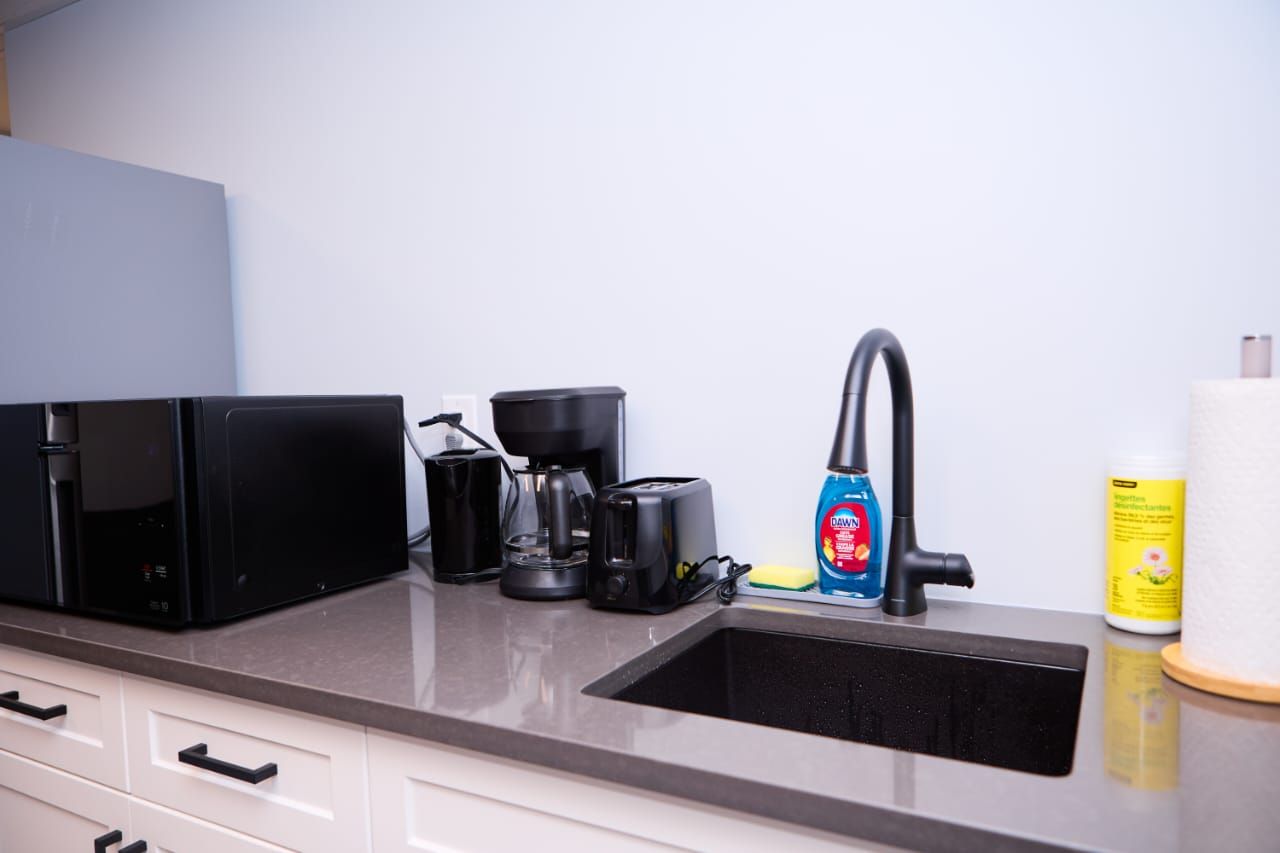 A kitchen with a coffee maker, toaster, and cleaning supplies.