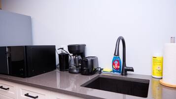 A kitchen with a coffee maker, toaster, and cleaning supplies.