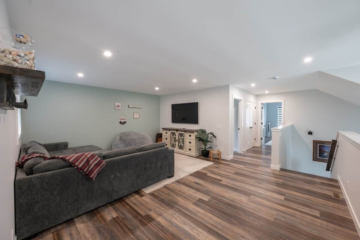 Una sala de estar moderna con un sofá, un televisor de pantalla plana y piso de madera.