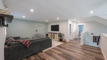 Una sala de estar moderna con un sofá, un televisor de pantalla plana y piso de madera.