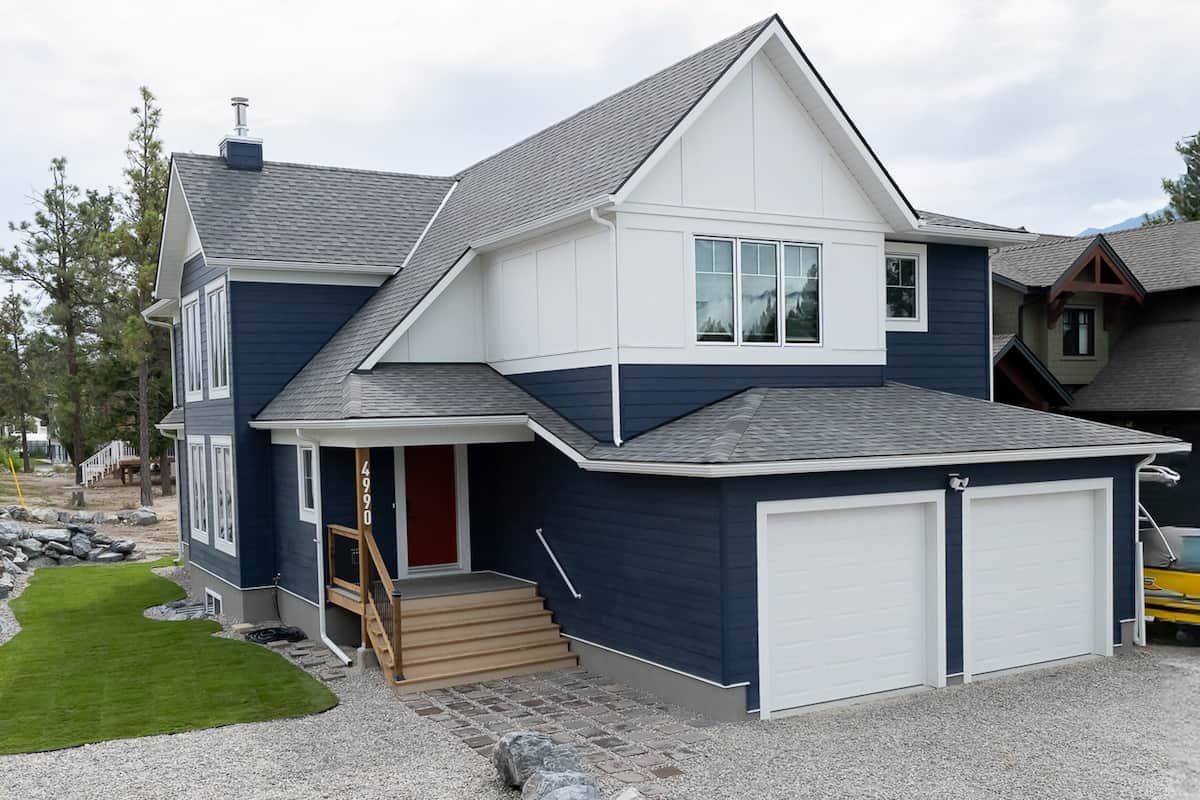 Une maison à deux étages avec un garage, un porche à l’avant et une pelouse bien entretenue.