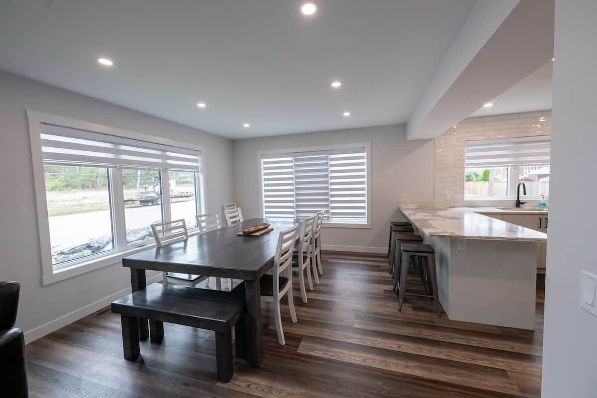 Una cocina moderna con comedor, ventanas amplias y una barra.