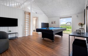 A room with a pool table, a TV mounted on the wall, and a view of the outdoors. - Cozy home in Hvide Sande with sauna (Hvide Sande)