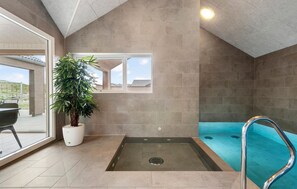 Área de spa com hidromassagem, uma planta em vaso e vista para o exterior.