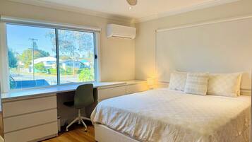 A bedroom with a large bed, a desk, and a window overlooking a street.