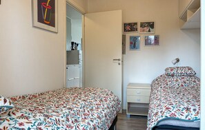 Ein Schlafzimmer mit zwei Betten, einem Kleiderschrank, einem Schreibtisch und einer Wand mit gerahmten Bildern.