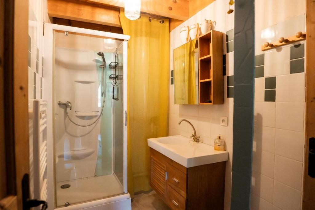 A bathroom with a glass-enclosed shower, wooden cabinets, and a white sink.