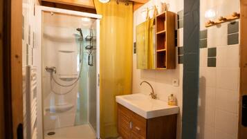 A bathroom with a glass-enclosed shower, wooden cabinets, and a white sink.