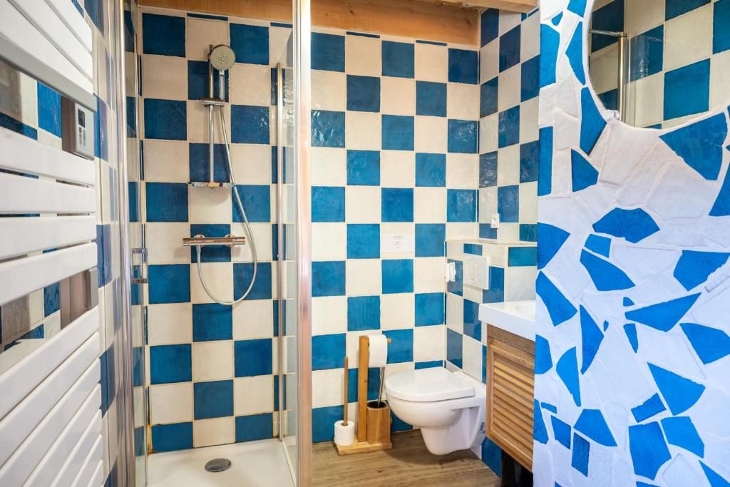 Een badkamer met een zwart-wit betegelde vloer, een douche, een toilet en een houten kastje.