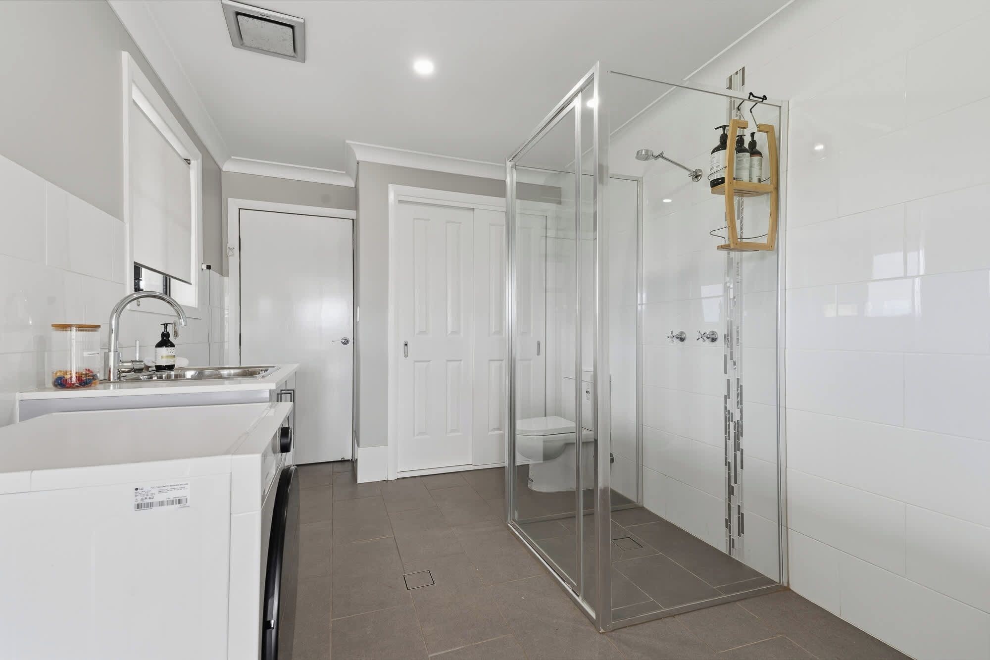 Un bagno moderno con doccia vetro, lavandino bianco e water.