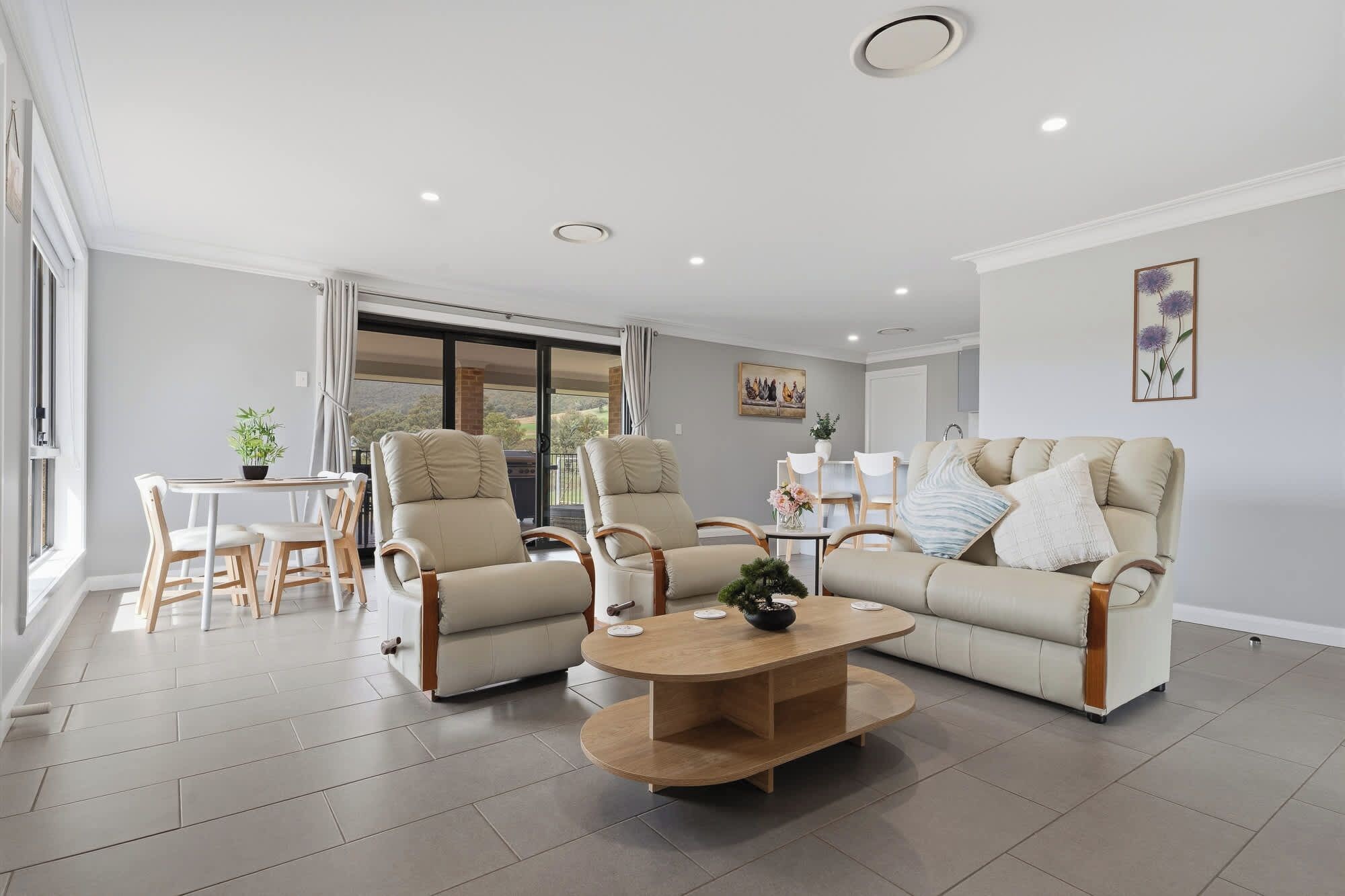 A modern living room with a sofa, two armchairs, a coffee table, and a dining area with a table and chairs.