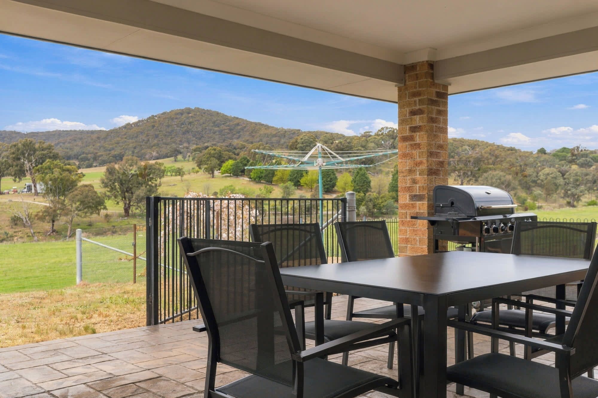 Eine Terrassengaststätte mit Tisch und Stühlen, einem Grill und Blick auf eine hügelige Landschaft.