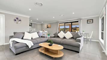 Ein modernes Wohnzimmer mit zwei grauen Sofas, einem Holztisch und einem Essbereich mit Tisch und Stühlen.