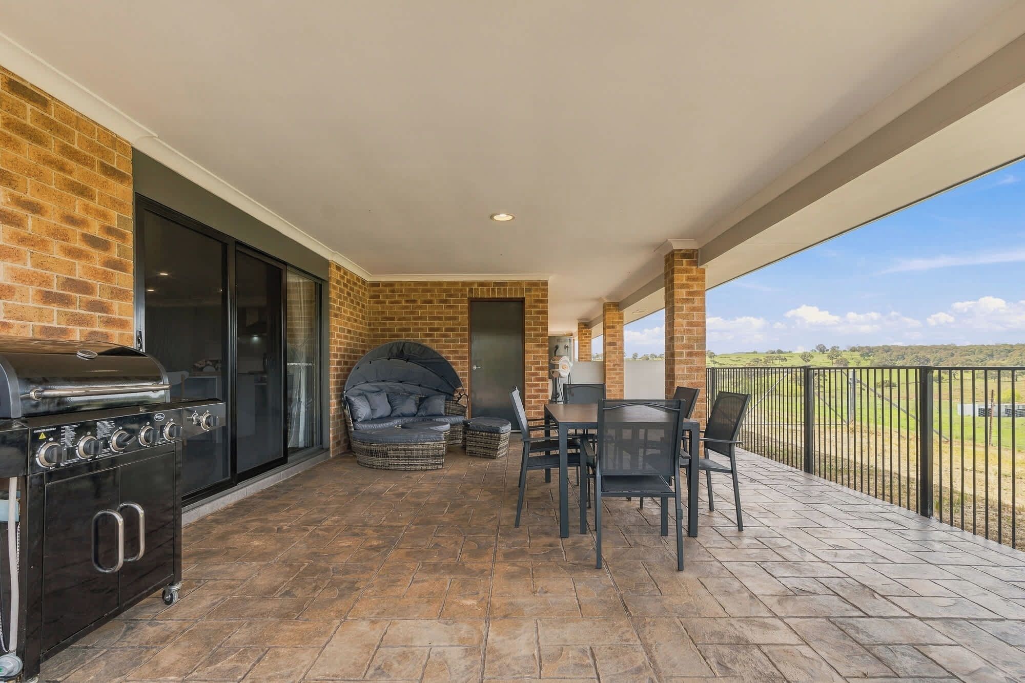 Eine überdachte Terrasse mit Grill, Sitzgelegenheit und Blick ins Grüne.