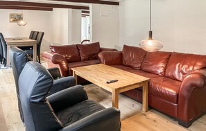 Ein Wohnzimmer mit einem braunen Ledersofa, einem Holztisch und schwarzen Ledersesseln.