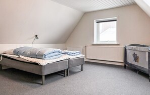 Ein Schlafzimmer mit einem Bett, einem Heizkörper, einem Fenster und einem Babybett.