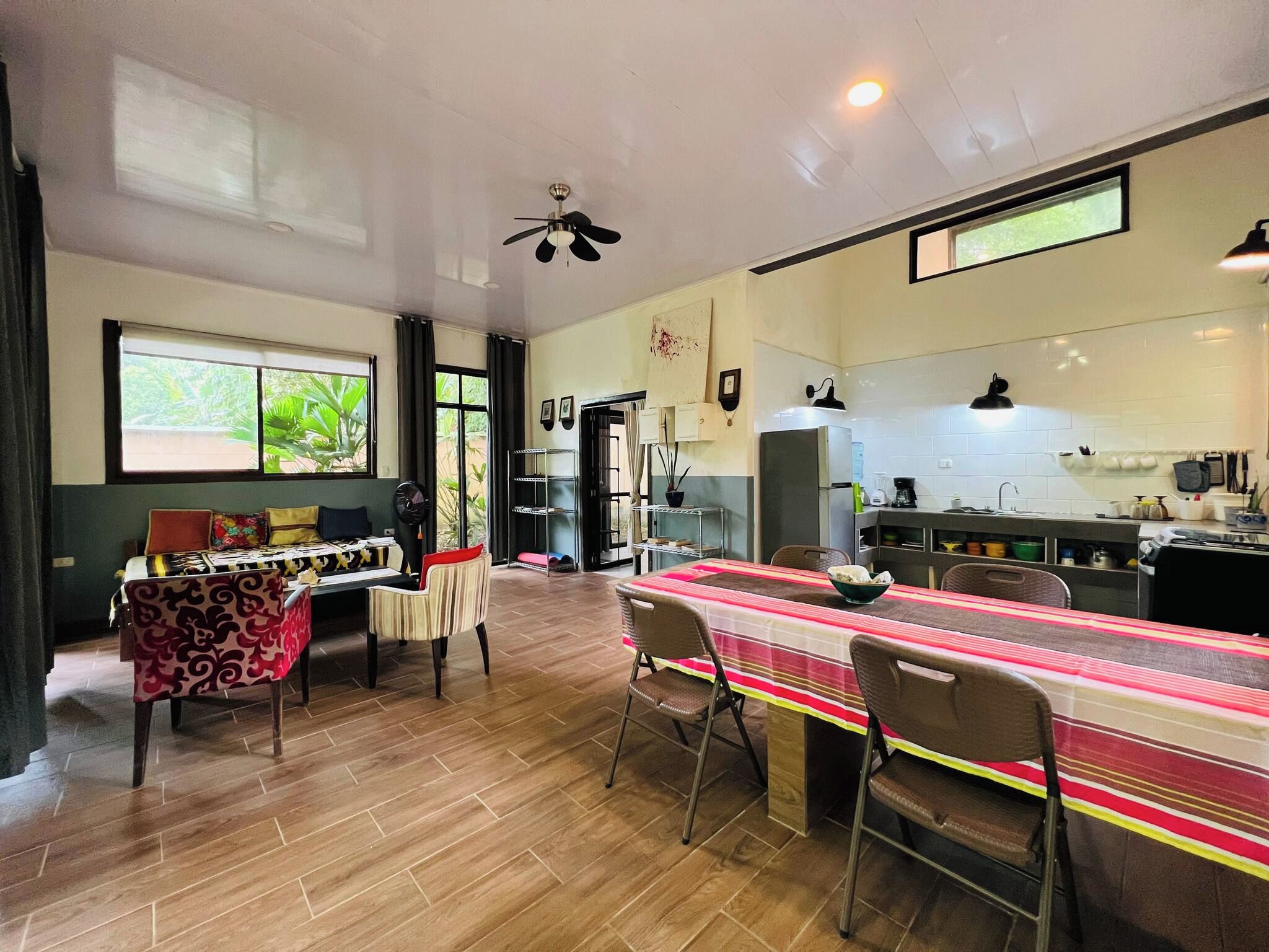 Una cocina amplia con zona de comedor, suelo de madera y ventilador de techo.
