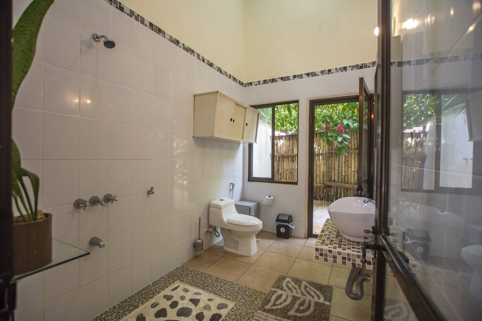 A bathroom with a toilet, sink, shower, and a glass-enclosed shower area.