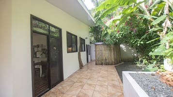 Un pasillo con suelo de baldosas, un banco de madera y una lámpara fijada a la pared.