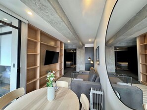 A modern interior with a dining area, built-in shelving, a flat-screen TV, and a cozy seating area. - w* | Bright 2BR w/ Terrace in Tabacalera (Ciudad de México)
