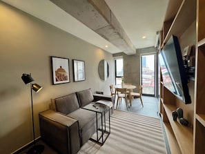 A modern living room with a sofa, a coffee table, a TV, and a dining area with chairs and a table. - w* | Bright 2BR w/ Terrace in Tabacalera (Ciudad de México)