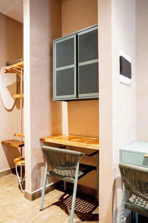 A corner room with a wooden desk, two wicker chairs, a wall-mounted TV, and a clothes rack. - w* | Deluxe 4BR in Prime Bocagrande (Cartagena de Indias)