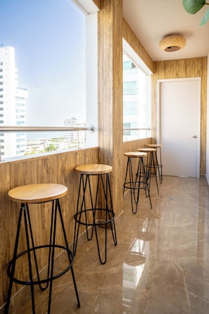 A modern interior with wooden accents, a balcony with a view of buildings, and a door. - w* | Deluxe 4BR in Prime Bocagrande (Cartagena de Indias)
