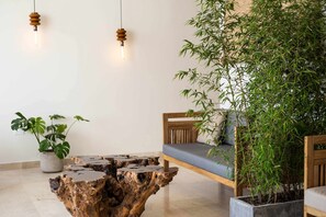 A wooden coffee table with a unique design, a wooden bench with cushions, and a large bamboo plant. - w* | Grand 4BR w/ Private Terrace in Bocagrande (Cartagena de Indias)