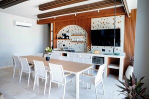 A modern kitchen with a central island, white cabinetry, and a large flat-screen TV mounted on the wall. - w* | Grand 4BR w/ Private Terrace in Bocagrande (Cartagena de Indias)