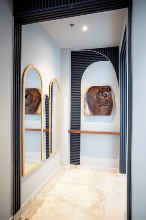 A hallway with a marble floor, a wooden bench, and three wall-mounted mirrors. - w* | Grand 4BR w/ Private Terrace in Bocagrande (Cartagena de Indias)