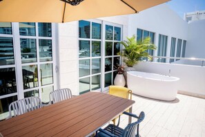 An outdoor seating area with a table and chairs, a large window, and a hot tub. - w* | Grand 4BR w/ Private Terrace in Bocagrande (Cartagena de Indias)