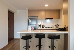 A modern kitchen with a central island, bar stools, and a coffee maker. - w* | Chic 2BR w/ Balcony & Sea View in Miraflores (Miraflores)