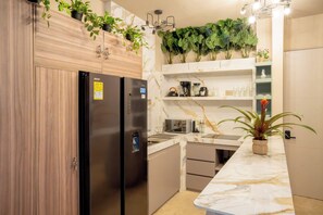 A modern kitchen with a marble countertop, built-in appliances, and decorative plants. - w* | Upscale 3BR in Prime Bocagrande (Cartagena de Indias)