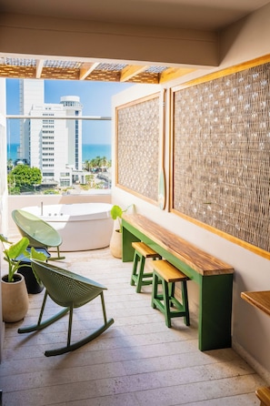 Ein Balkon mit Sitzgelegenheit, einem Schaukelstuhl und Blick auf die Stadt.