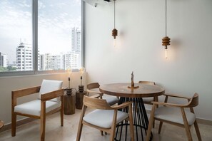 A modern dining area with a round wooden table, six wooden chairs, and pendant lights. - w* | Signature 2BR w/ AC in Bocagrande (Cartagena de Indias)