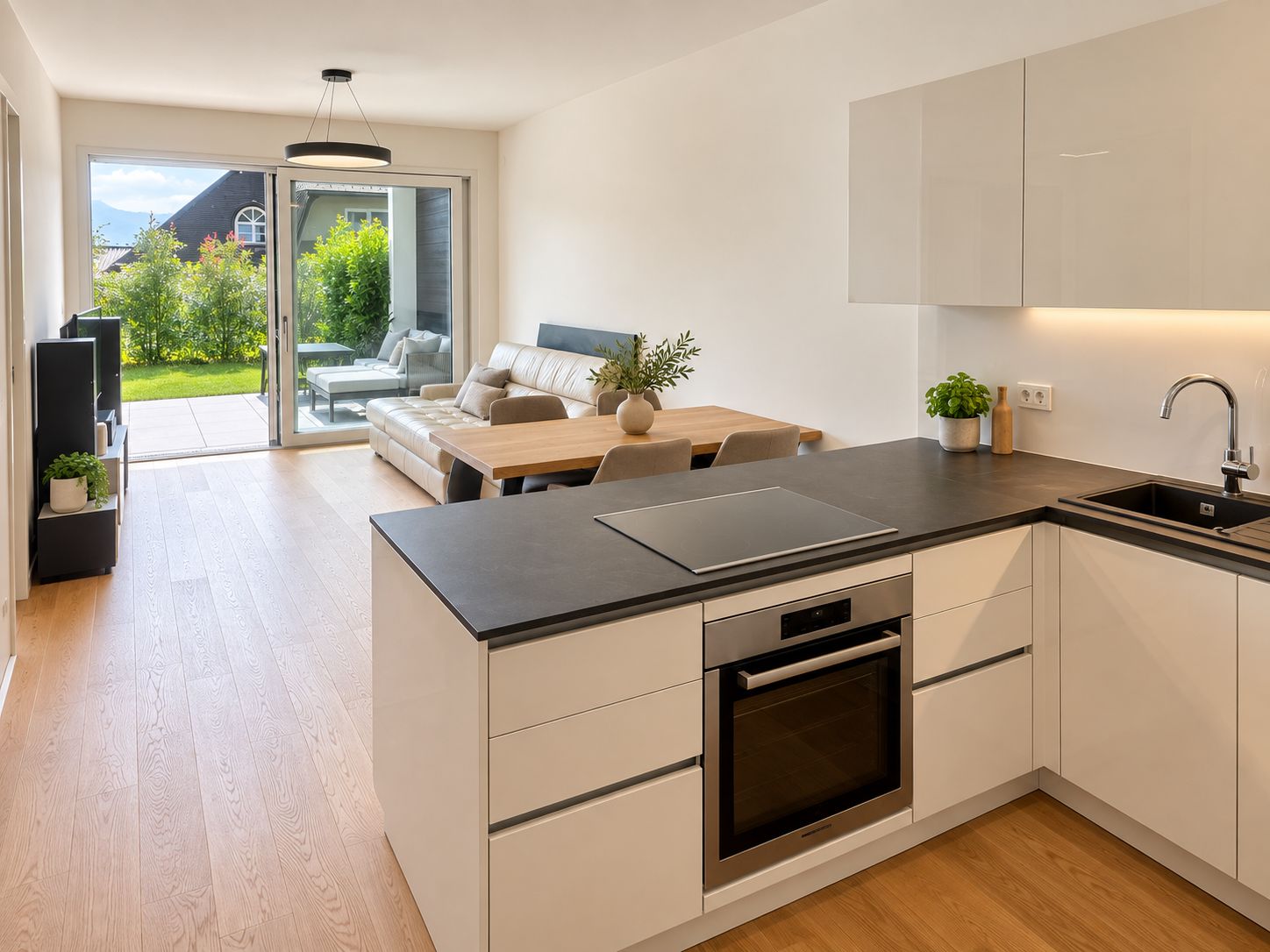 Eine moderne Küche mit Einbauofen, einem Essbereich mit Tisch und Stühlen sowie einer Schiebeglastür, die auf eine Terrasse mit Gartenmöbeln führt.
