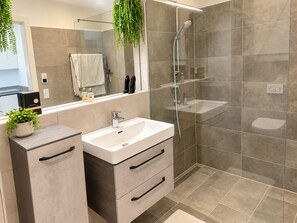 A modern bathroom with a glass-enclosed shower, a double sink vanity, and a mirror above the vanity. - Premium garden apartment on the Kreuzbergl near Lake Wörthersee, the University, and Lakeside (Klagenfurt am Wörthersee)