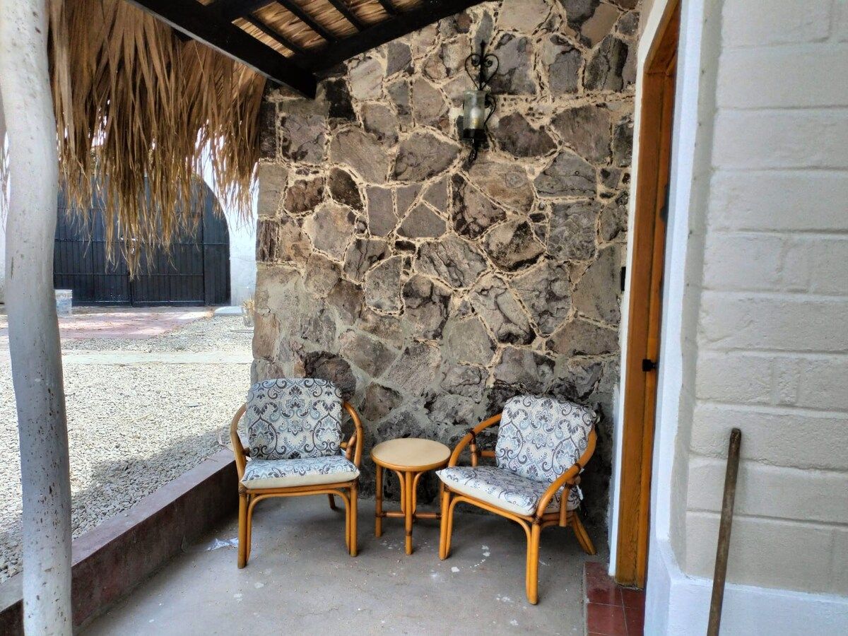 A stone wall with two wicker chairs and a small round table.