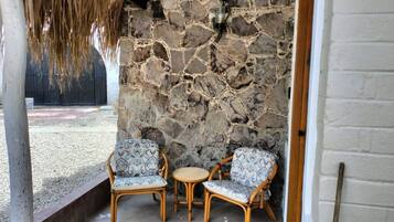 A stone wall with two wicker chairs and a small round table.