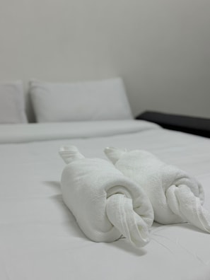 A neatly made bed with white linens and two rolled towels placed on the bed. - Global Sea View Hotel (Tambon Patong)