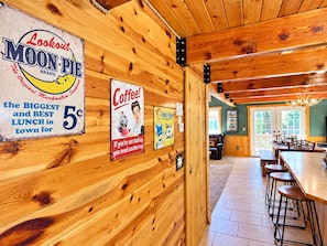 A wooden interior with a dining area, a kitchen, and a sign advertising a 5-cent lunch. - Hot Tub | 32 Miles to Yellowstone | Fire Pit (Island Park)