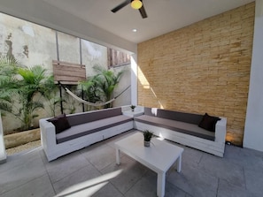 A modern outdoor seating area with a white sofa and a coffee table, a hammock, and potted plants. - Modern Rutelena Villa, sleeps 12, private pool, 5 min to 5th Street, the beach, and the supermarket (playa del carmen)