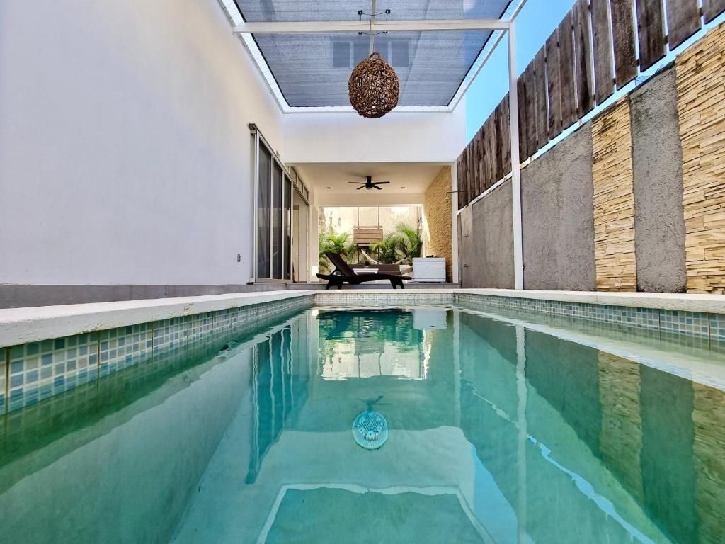 Una piscina con un ventilador de techo, una tumbona y vistas al exterior.